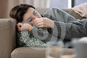 sad crying woman with tissue lying on sofa at home