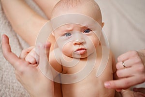 sad cute naked baby lies on his mother's feet. maternal and child health.