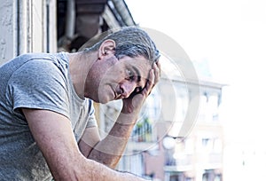 sad and depressed 40s man looking through outdoors at home balco