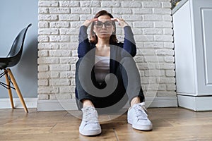 Sad depressed age lonely woman sitting on floor.