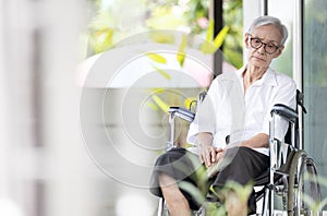 Sad and depressed asian senior woman sitting alone in wheelchair with head down feel lonely and bored,disabled old elderly with