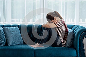 Sad and depressed Asian women sitting on couch at home