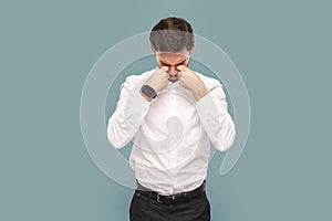 Sad depressed crying man standing and rubbing his eyes, being in bad mood and having stress.