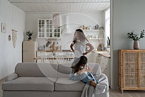 Sad depressed girl daughter sitting on sofa hugging pillow and crying while mom scolding her at home