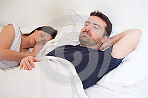 Sad and depressed man lying in the bed with wife