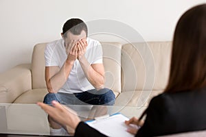 Sad depressed man at the psychologist, feeling hopeless and desp photo