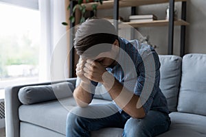 Sad depressed man sit on sofa with head-down