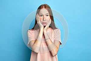 Sad depressed offended woman with holding hands on cheeks looking at camera