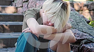 Sad depressed teenage girl alone on the steps outside feeling angry and lonely.