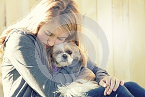 A sad or depressed teenage girl hugging a small dog