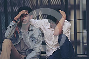 Sad Depressed two Insomnia Men. Sitting on the street sidewalk after lost job. Young jobless man suffering depression sitting on