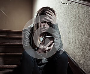 Sad depressed unhappy teenager girl suffering from cyberbullying by mobile smart phone sitting alone