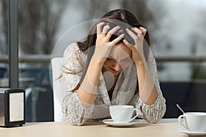 Sad and depressed woman alone in a coffee shop photo