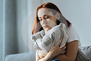 Sad depressed woman hugging a cushion