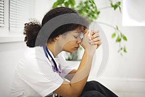 Sad depressed young african american nurse sitting on floor with frustrated face expression