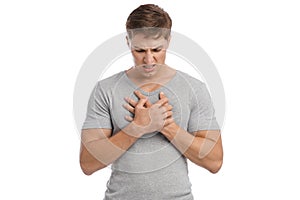 Sad despaired millennial caucasian handsome guy presses hands to sore spot and suffers from chest pain