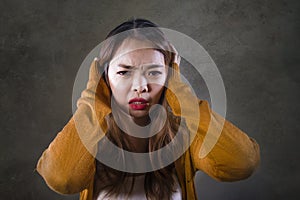 Sad and desperate Asian Korean woman holding her head depressed feeling anguish and pain on isolated dark background in pain face