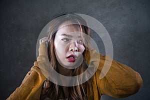 Sad and desperate Asian Korean woman holding her head depressed feeling anguish and pain on isolated dark background in pain face