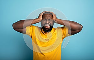 Sad and desperate expression of a boy who is scared to catch the covid-19 coronavirus. Cyan background.