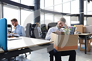 Sad dismissed worker are taking his office supplies with him from office