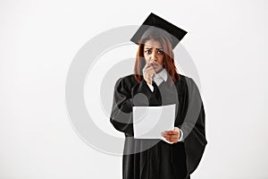 Sad displeased african female graduate looking at camera holding test over white background.