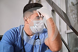 Sad doctor in facial mask indoors. Stress of health care workers during coronavirus pandemic