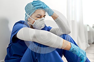 Sad doctor or nurse in face mask holding to head