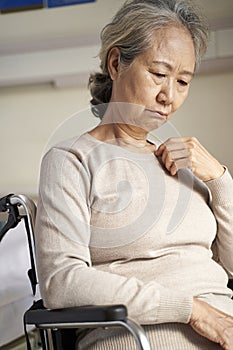 Sad elderly asian woman sitting in wheelchair in nursing home