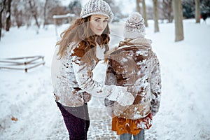 Sad elegant mother and child shaking snow off clothes