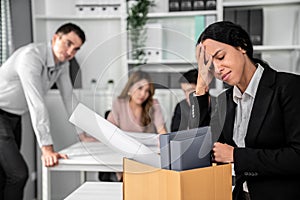 Sad employee packing her belongings after being fired for not being competent.