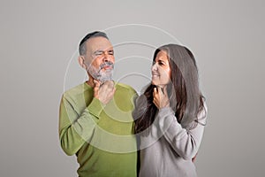 Sad european old couple suffer from sore throat, tonsillitis on gray studio background