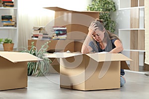 Sad evicted woman moving out packing boxes at home photo