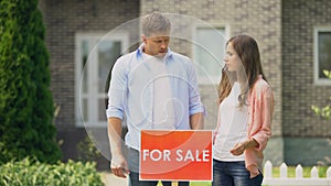 Sad family installing for sale signboard, have to sale their big house, crisis