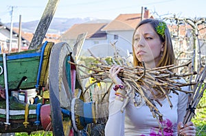 Sad farm girl holding wooden wite in a backyard with an old colo