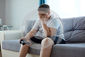 Sad fat boy is upset after losing a video game photo