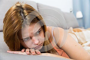 sad female on cozy sofa at home