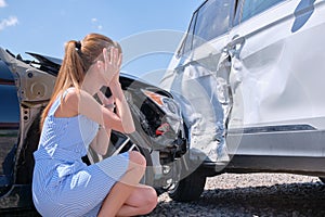 Sad female driver sitting on street side shocked after car accident. Road safety and vehicle insurance concept