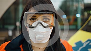 Sad female paramedic stares at you feeling alert standing near ambulance