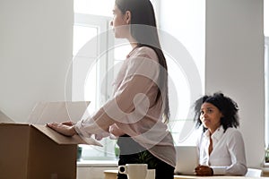 Sad fired or dismissed female employee packing box in office