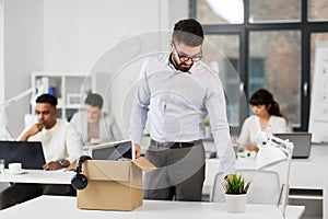 Sad fired male office worker with personal stuff