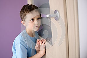 Sad, frightened child listening to a parent talking through the door photo