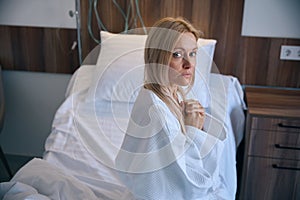 Sad frightened woman sitting all alone in inpatient facility room