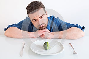 Sad and frustrated man on diet having only vegetables for meal