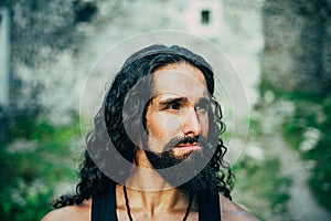 Sad frustrated man with long dark wavy hair and beard looking far away. Portrait of handsome man with disappointed face