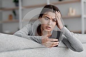 Sad frustrated shocking european young woman suffering from depression and reading message with bad news