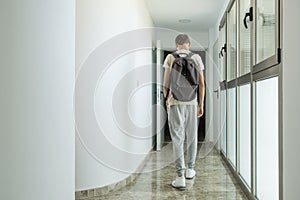 Sad frustrated teenage boy walks away down school corridor alone. Education difficulties, problem with family, emotion