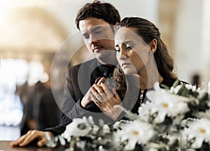 Sad, funeral and flowers with couple and coffin in church for death, respect and mourning. Grief, goodbye and empathy