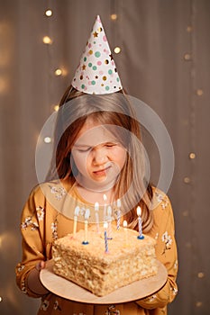 Sad girl with birthday cake. tradition to make wish and blow out fire