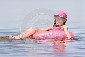 Sad girl in a cap floating in river sat on the swimming circle