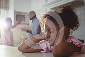 Sad girl fed up of her parents arguing in kitchen